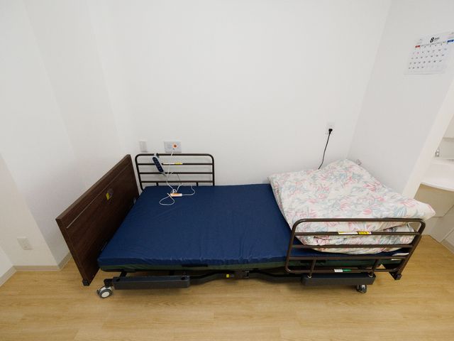 シンプルな居室のベッド 介護ベッド 機能的なベッドが配され、快適な睡眠環境を整えた明るい居室です。プライバシーにも配慮した空間設計となっております。