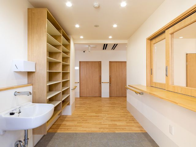 清潔な廊下の一角 エントランス 手すり付きの広々とした廊下は、歩行に不安を感じる方でも安心して移動できる配慮がされています。壁に取り付けられた棚は、小物の整理に便利です。