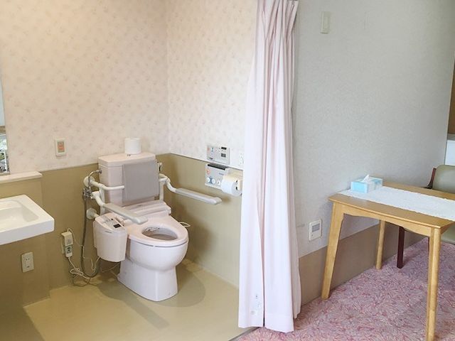 明るい色合いのトイレ空間 設備 手すり付きの設備と柔らかな色調で、利用者の快適性を考えた空間です。