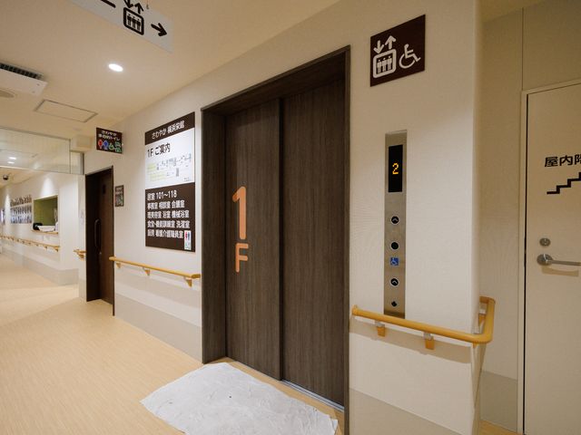 廊下と扉の細部 エレベーター 清潔感あふれる廊下は、手すりも完備しており、安全に配慮された設計です。明瞭な案内表示で、利用者の方の移動もスムーズです。