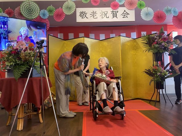 敬老祝賀会の様子 多目的室 敬老祝賀会のイベントが行われています。スタッフが手伝い、心温まる雰囲気です。