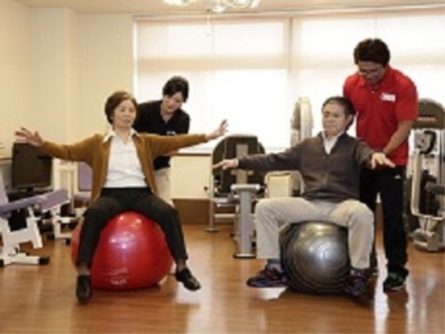 職員が支援する姿 機能訓練室 スタッフが優しく支えながらトレーニングを行う、活気ある職場環境です。