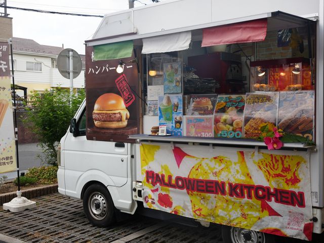 移動販売車　屋外 外観 キッチンカーからはさまざまなメニューが提供され、賑やかな雰囲気が感じられます。