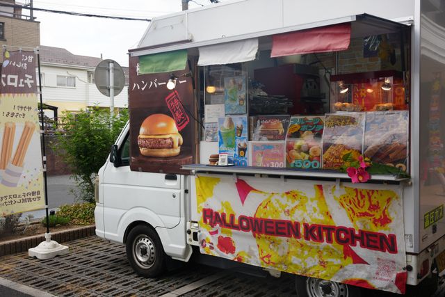 移動販売車　屋外 外観 キッチンカーからはさまざまなメニューが提供され、賑やかな雰囲気が感じられます。