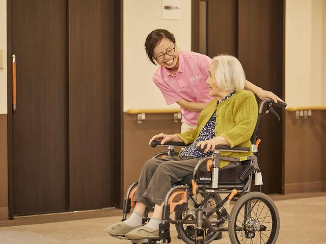 感じの良いスタッフと利用者 施設内の様子 笑顔で接するスタッフの姿が印象的です。あたたかな雰囲気の中で、ご利用者様の快適な生活を支えています。