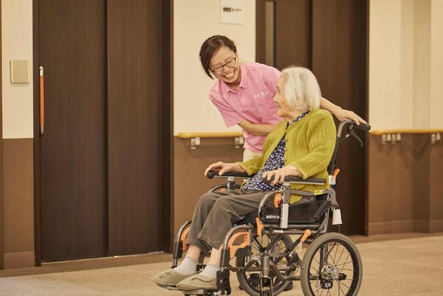 感じの良いスタッフと利用者 施設内の様子 笑顔で接するスタッフの姿が印象的です。あたたかな雰囲気の中で、ご利用者様の快適な生活を支えています。