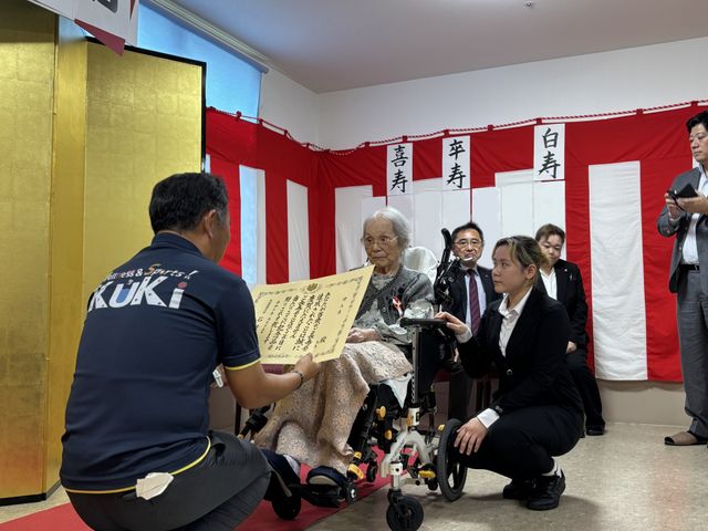 表彰中の居室 居室 車椅子に座った方が特別な表彰を受けています。人々が暖かく見守る和やかな空間です。