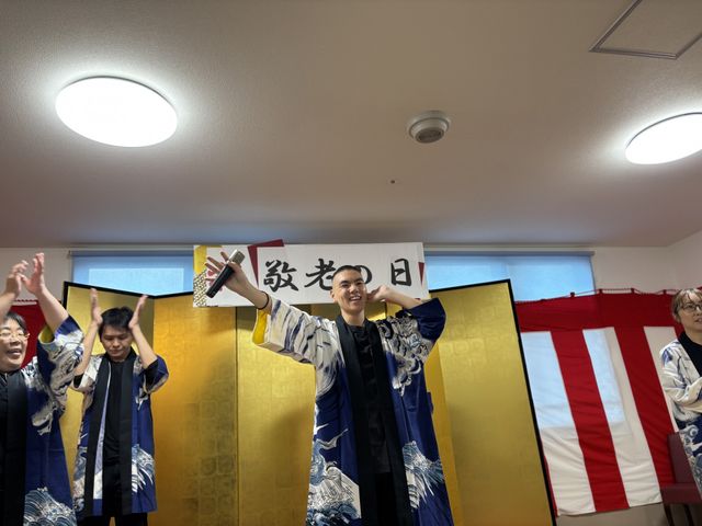 イベントの様子 多目的室 伝統的な衣装を着たスタッフが楽しい演技を披露しています。明るい多目的室で、行事が行われています。