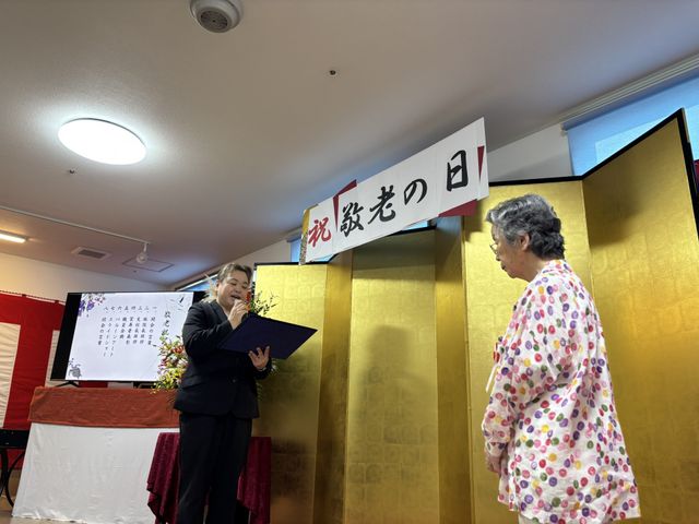 敬老の日の祝いの様子 多目的室 広々とした多目的室で、敬老の日の式典が行われております。温かみのある内装が魅力的です。