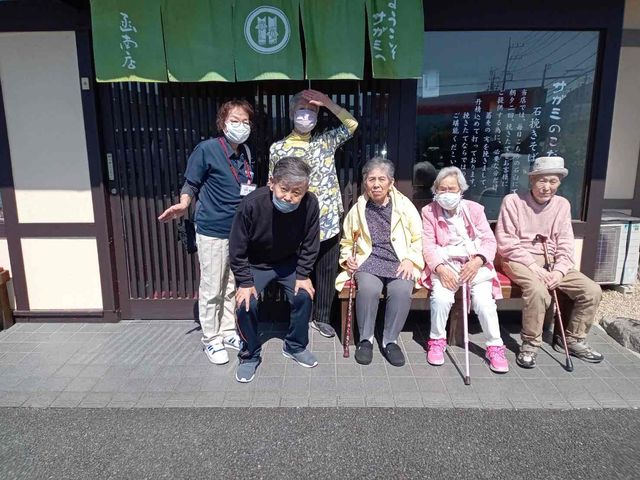 入り口前の集い 外観 建物の前で、笑顔のメンバーがくつろいでいます。和やかな雰囲気が魅力的です。