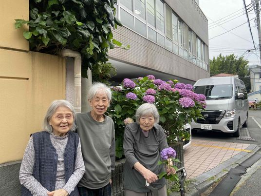 紫陽花の前で微笑む人々と建物外観