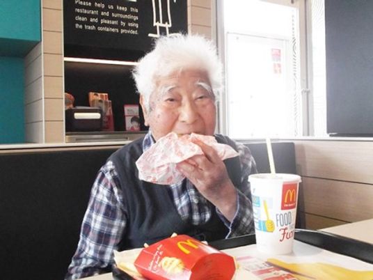 高齢者がハンバーガーを食べる様子