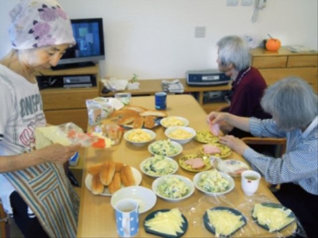 共同料理する人々 食事 手作りの温かい料理を囲んで、入居者同士のコミュニケーションが楽しめる食堂です。日常のふれあいが魅力的な環境を提供しています。