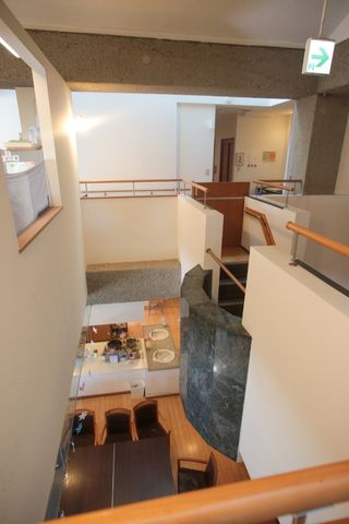 多層構造の共用スペース 共有スペース 広々とした開放感ある多目的室で、入居者様が憩いのひとときを過ごされています。吹き抜けのデザインが特徴的です。