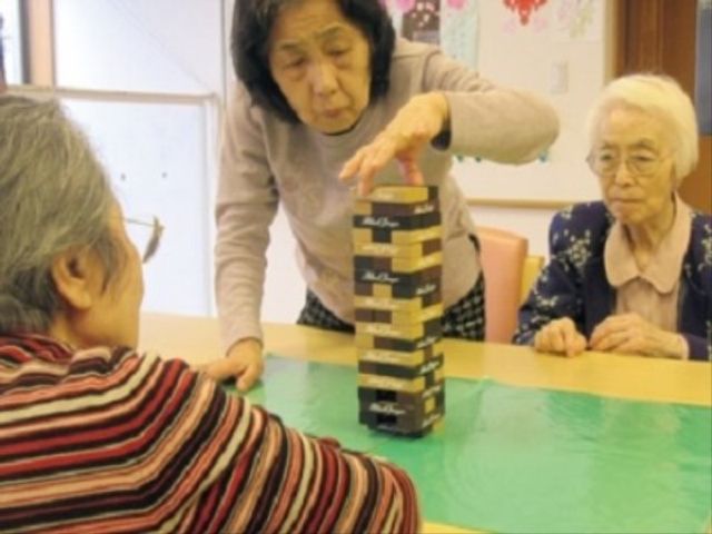 高齢者がゲームを楽しむ ゲーム 楽しげな雰囲気のあるゲームの時間です。参加者はコミュニケーションを取りながら、積み木ゲームを心地よく楽しんでいます。