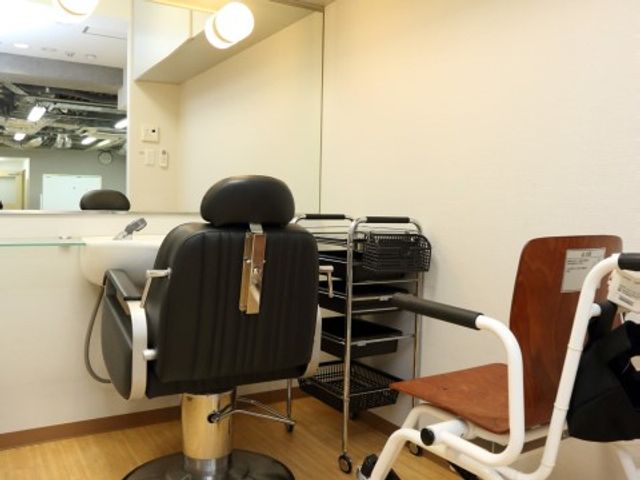 理美容席と鏡の一角 理美容室 明るく清潔感のある理美容室です。利用者の方が心地よく過ごせるよう配慮された設計となっております。