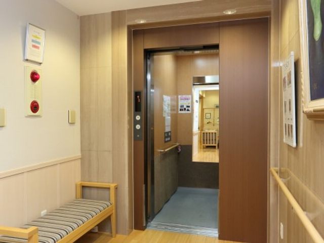 清潔な施設のエレベーター エレベーター 手すりが設置されたエレベーター前です。通路と合わせて明るく安全な移動が支援されています。