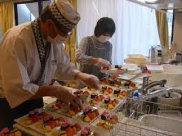 調理スタッフと食事準備 レクリエーション 調理スタッフが手際よく彩り豊かな食事を準備しており、新鮮な果物が添えられたデザートが印象的です。働く上でのやりがいを感じられる職場の一コマです。