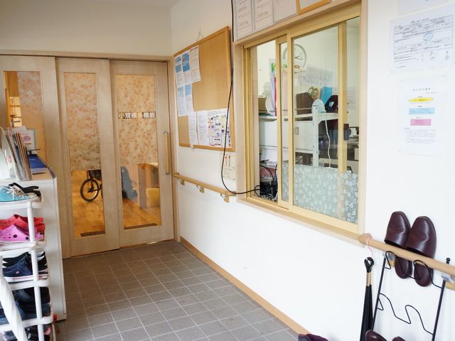 事務室入口と掲示物 エントランス 開放的な通路には掲示板があり、職員が働く様子が透明な窓越しに見えます。利用者の皆さまが日々の情報を手に取れる配慮が行き届いています。