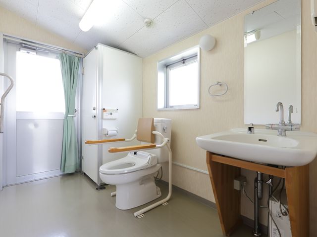 車椅子対応の洋式トイレ 共用トイレ 広々とした清潔なトイレです。手すりや補助席も設置され、どなたでも安心してご利用いただけます。