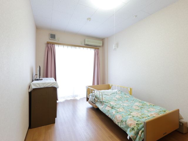居室の単身用ベッド 居室(一例) 広々とした個室で、清潔感のあふれるベッドと窓から自然光がたっぷりと差し込む様子がうかがえます。明るく落ち着いた雰囲気で、快適な生活をサポートします。