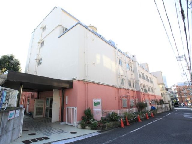 ピンクの建物のエントランス 外観 広々として明るいエントランスは、来訪者を温かく迎え入れます。身体が不自由な方も安心してお越しいただける設計がされています。