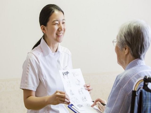 笑顔で説明するスタッフ 医療サポート 笑顔でリハビリ計画を説明するスタッフの様子です。利用者の方との心温まるコミュニケーションが垣間見えます。