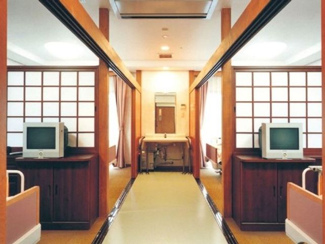 温かみのある廊下 居室 落ち着いた色合いの廊下は、和風のデザインが特徴です。訪れた方々に安らぎを提供する空間が広がっています。