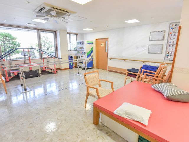 機能訓練室とリハビリ訓練器具 機能訓練室 広々とした機能訓練室で、明るい自然光が差し込む環境です。多様なリハビリ訓練器具が整っており、専門のスタッフによるサポートが受けられます。