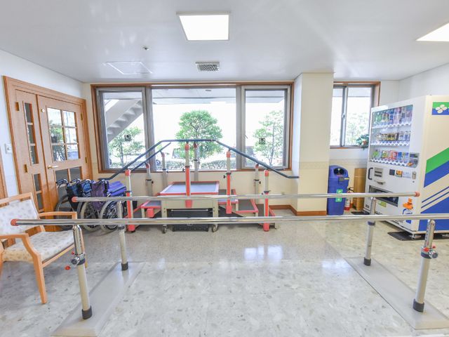 機能訓練用具と広い窓 機能訓練室 広々としたトレーニングスペースで、明るく快適な環境が整っています。様々なリハビリ機器がそろい、安全な日々の支援をめざしています。