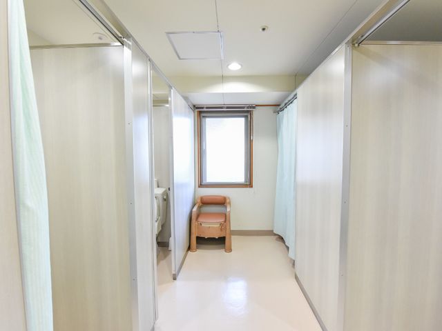 清潔なトイレの個室 トイレ横通路 プライバシーを配慮した個別のトイレスペースです。清掃が行き届き、清潔で明るい環境を保っています。