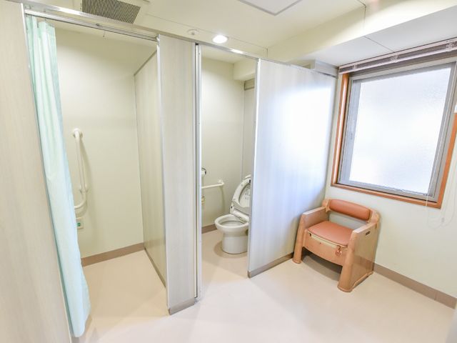バリアフリー設計のトイレ ポータブルトイレ 手すり付きで安全性を考慮したトイレの様子。ゆったりしたスペースが確保されており、使いやすさに配慮されています。