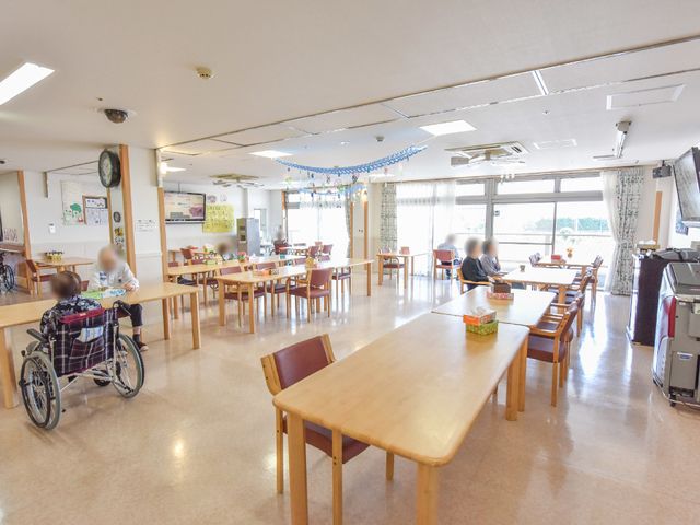 明るい広々とした食堂 食堂兼デイルーム 住居者がリラックスして食事を楽しめる広々とした空間です。車椅子の方も快適に過ごせる配慮がなされています。