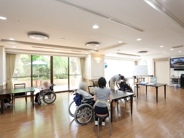 多目的室でのお手伝い 食堂 明るく居心地の良い多目的室です。スタッフが丁寧にサポートしており、利用者の安心感を大切にした雰囲気が伝わります。