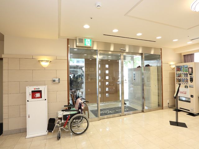 広々とした明るいエントランス エントランス 車椅子を利用している方がいらっしゃいます。また、清潔感のある床や落ち着いた色合いの壁が、安心感を与えるエントランスになっています。