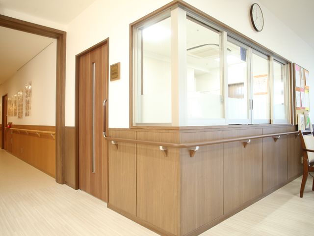 快適なフロント兼廊下 通路 清潔感のあふれる木目調のフロントスペースです。掲示板や時計も備え、情報共有に役立っています。