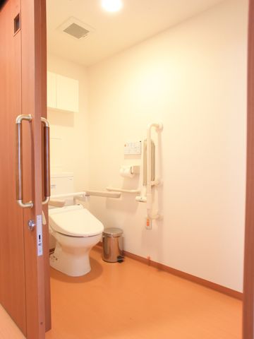 バリアフリー設計のトイレ 居室トイレ  快適にご利用いただけるよう、手すりが設置された清潔なトイレです。ゆったりとした空間は、利用者の安全と快適さを考慮しています。