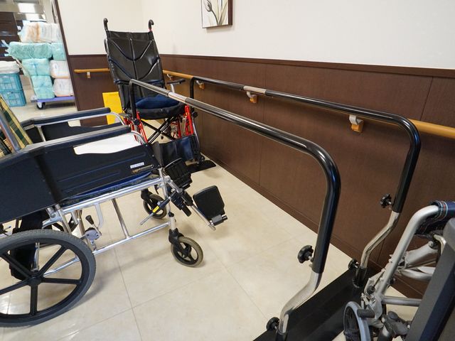 廊下に配された車椅子 廊下 手すりが整備された廊下は、移動をサポートし、安心して過ごせる設計になっています。車椅子もきちんと整理され、利用しやすい環境です。