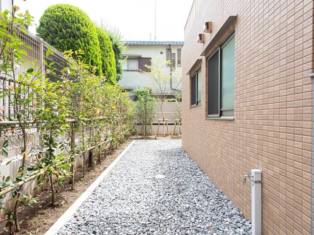 植栽のある通路 庭   建物脇の細長い通路に、植栽が並ぶ落ち着いた外まわりです。自然を感じられる環境で、散歩や気分転換もしやすそうです。