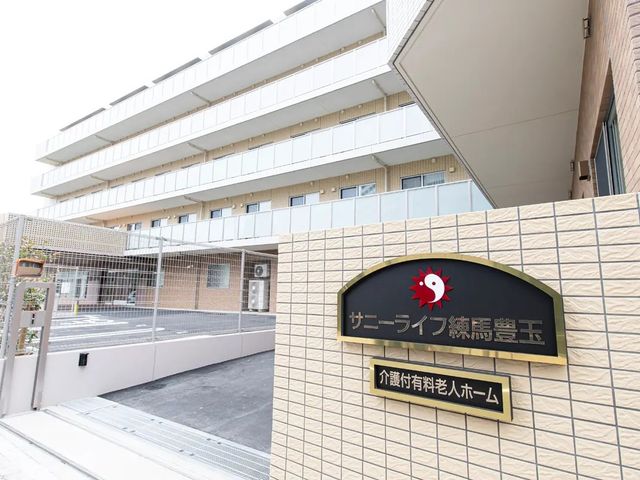 施設の外観案内板 外観   明るい外壁とバルコニーが印象的な建物です。入口には施設名の案内板があり、来訪時にわかりやすいです。