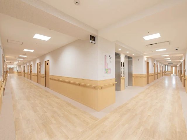 明るい廊下 廊下   木目調の床と手すりが続く、明るく広い廊下です。居室が両側に並び、移動しやすい印象です。