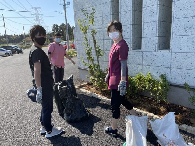 清掃する職員の外観 外観   建物のそばで清掃作業をする職員の方々が見えます。日差しの入る屋外で、施設まわりを整える様子です。