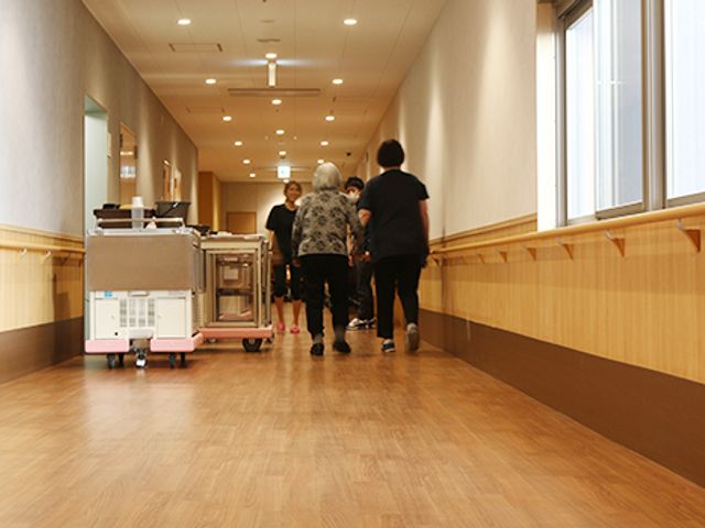 廊下 廊下 手すりが設置された廊下では、スタッフが集まって作業をしています。移動のしやすさが考慮されています。