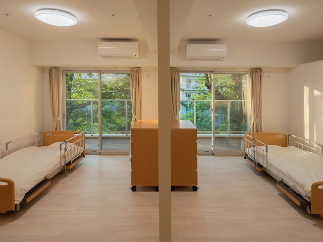 明るい二人部屋の居室 居室   大きな窓から自然光が入る、明るく落ち着いた居室です。ベッドが2台あり、中央に収納家具が配置されています。