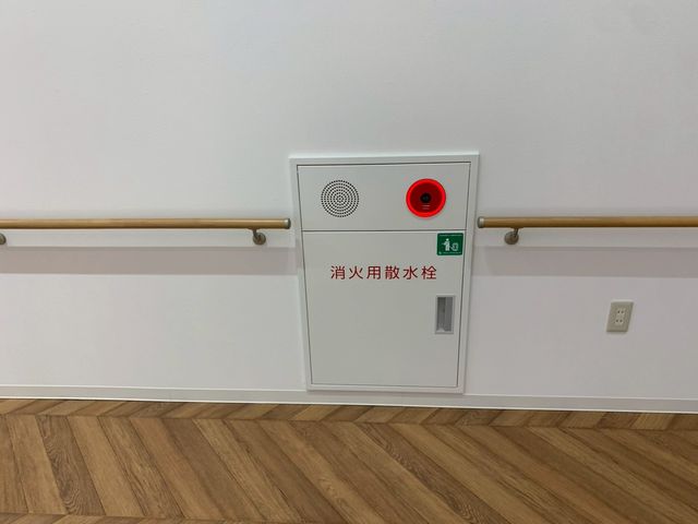 廊下の消火用散水栓 廊下   手すりが続く明るい廊下に、消火用散水栓が設置されています。安全面への配慮がうかがえます。