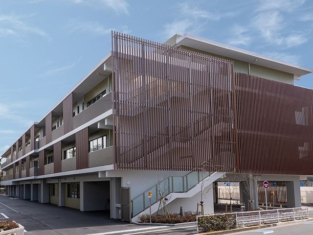 モダンな外観の建物 外観   木調のルーバーが印象的な、落ち着いた雰囲気の建物です。青空の下で、すっきりとした外観がよく見えます。