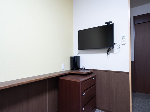 居室のテレビと家具 居室 清潔感のある居室では、壁掛けのテレビでリラックスした時間を過ごせます。必要な物を整理できる家具も完備しています。