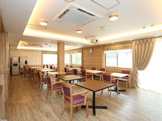 明るい食堂の様子 食堂 広々とした清潔感のある食堂では、ご利用者様が心地よい食事の時間を過ごされています。窓からは自然光が差し込み、開放的な雰囲気が演出されています。