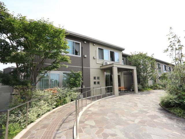 緑豊かな施設の外観 外観 自然に囲まれた施設の入り口は、バリアフリー設計で安心してお過ごしいただけます。緑と共に癒しのひとときを提供いたします。