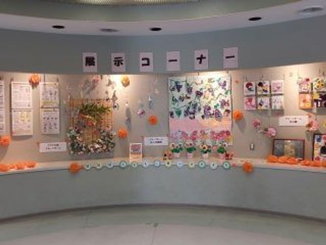 掲示物の並ぶ曲面壁の展示室 掲示物   壁いっぱいに作品や飾りが並び、明るく楽しい雰囲気です。利用者の方の活動が伝わりやすい、見せ方に工夫のある空間です。